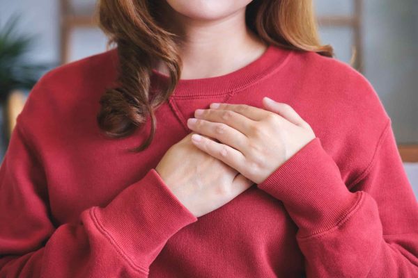 Woman in a red sweater with her hands on her chest